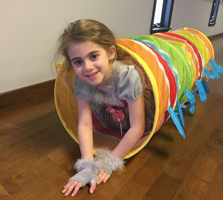 Young girl crawling through a play tunnel